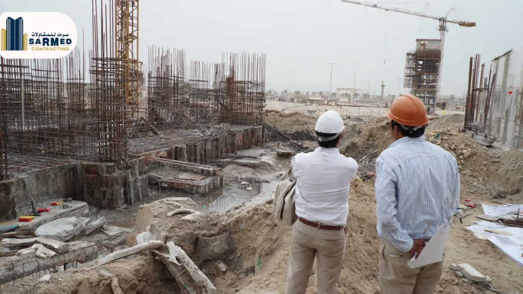 What Really Defines Quality Civil Work in Ajman? Two civil engineering site supervisors at a Sarmed Contracting project in Ajman, overlooking a foundation excavation and rebar installation to ensure every structural detail aligns with the original architectural blueprints.